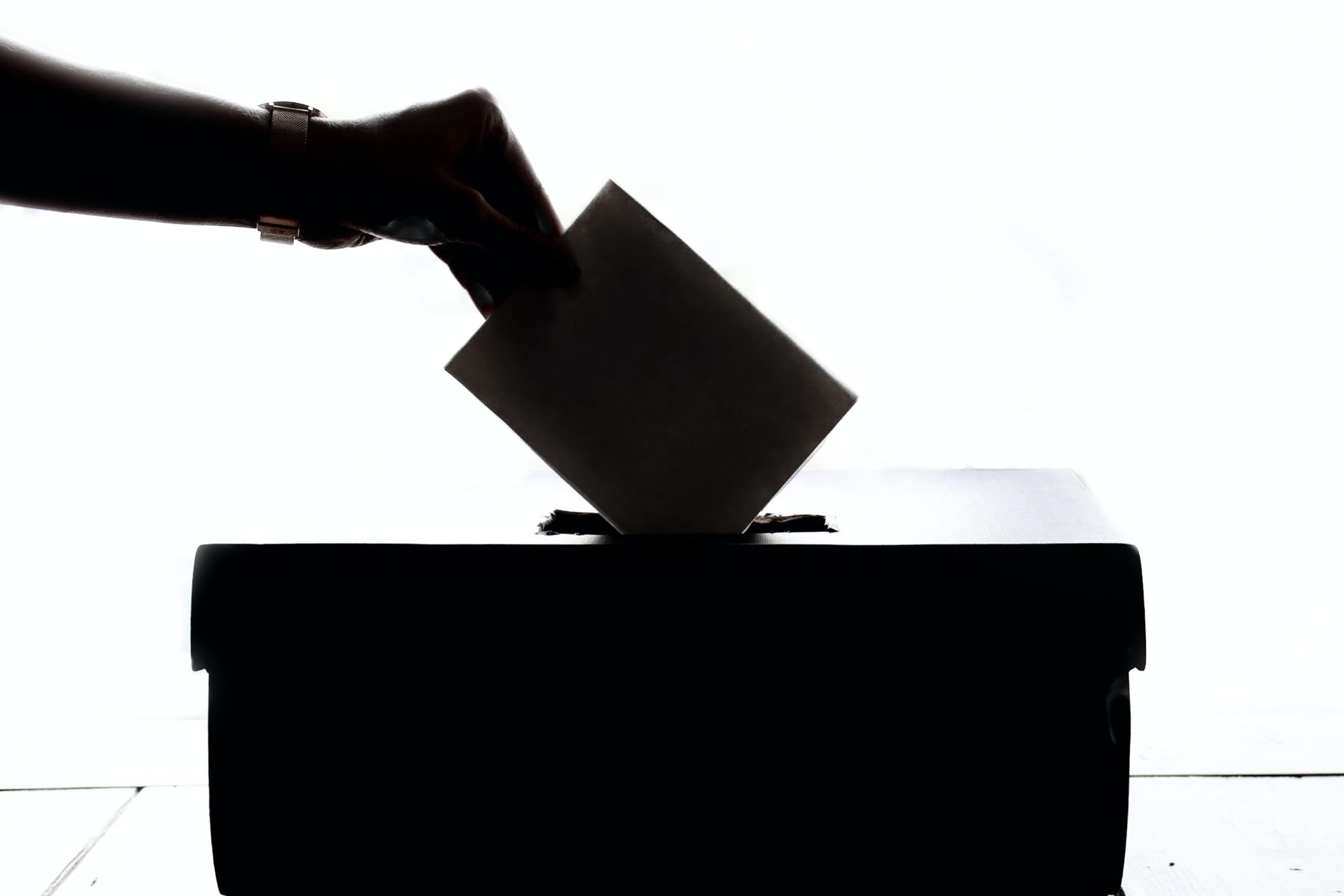 A hand putting a voting card in a ballot box